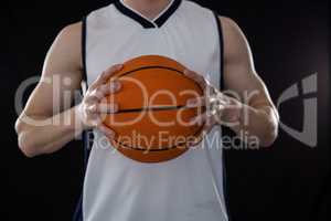 Player holding basketball against black background