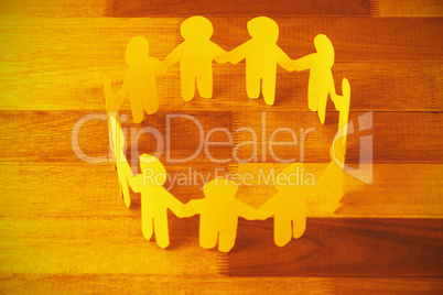Yellow paper cut out figures formimg circle on wooden table