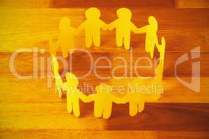 Yellow paper cut out figures formimg circle on wooden table