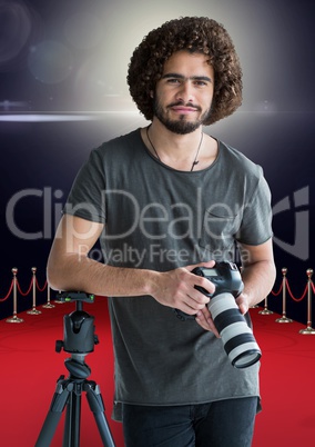 photographer rest on tripod, with the camera on hands in the red carpet. Flares behind