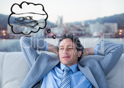Business man on couch dreaming of holiday against blurry skyline