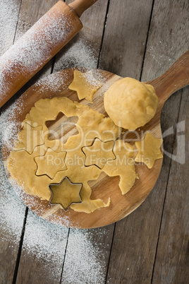 Overhead view of dough on cutting board with star shape cutter