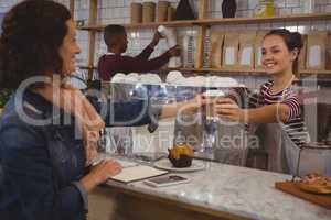 Female owner serving coffee to customer