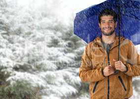 Man with blue umbrella in snow forest