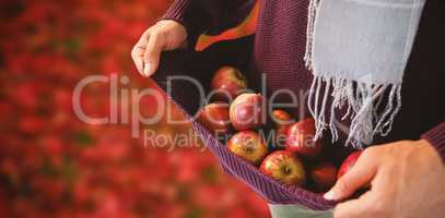 Composite image of mid-section of man carrying apples in sweater