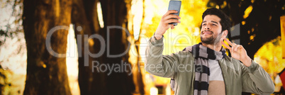 Composite image of smiling man taking selfie through mobile phone