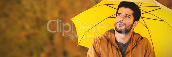 Composite image of thoughtful man with yellow umbrella