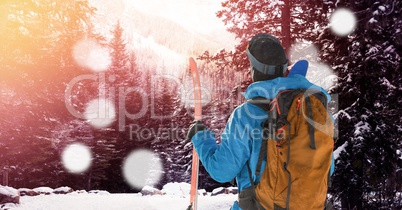 man standing with skies in forest