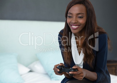 Businesswoman playing with computer game controller with bedroom background