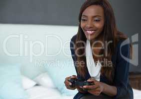Businesswoman playing with computer game controller with bedroom background