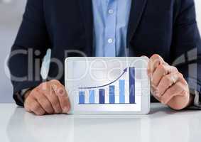 Businessman with tablet at desk and bar chart arrow