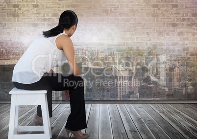 Businesswoman sitting on stool looking out over city