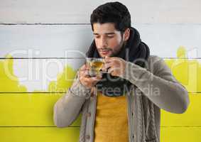 Man against wood with cup of golden liquid and warm scarf