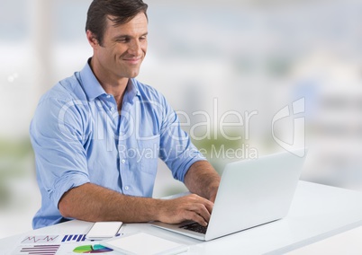 Businessman with laptop at desk with bright background