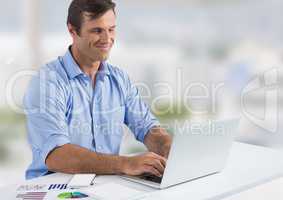 Businessman with laptop at desk with bright background