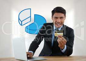 Businessman with laptop at desk with diagram of pie chart and bank card