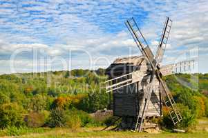wooden windmill in field and sky