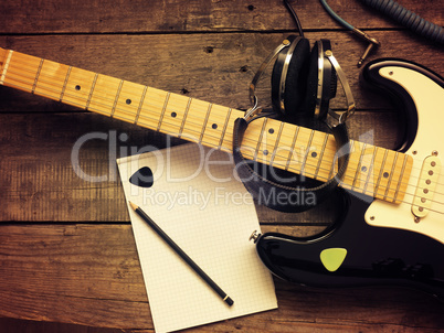 Vintage guitar with old studio headphones on wood