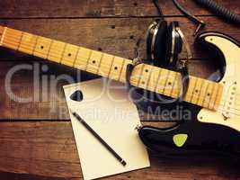 Vintage guitar with old studio headphones on wood