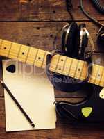 Vintage guitar with old studio headphones on wood