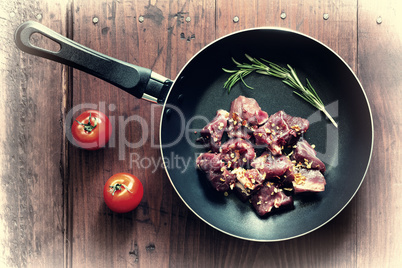 Concept: home cooking.Raw goulash beef in a frying pan with rosemary and spices.
