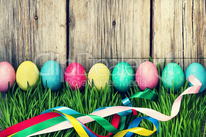HAPPY EASTER Easter eggs in a green grass on a wooden background, authentic Easter decorations.