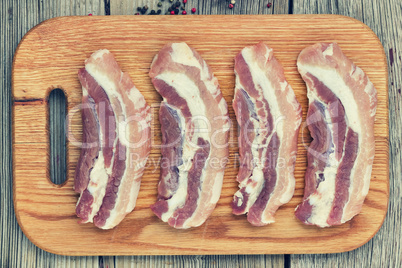 Raw steaks on a cutting board. Bacon.