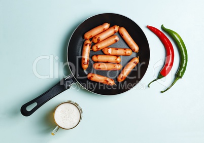 Beer and sausages fried in a frying pan, a top view, blue background.