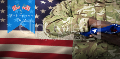 Composite image of mid section of soldier holding american flag