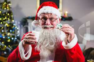 Santa Claus having christmas cookie with a glass of milk