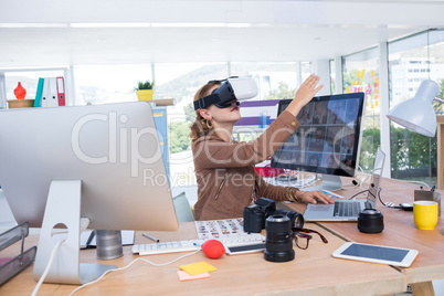 Female executive working on laptop while using virtual reality headset