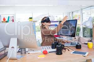 Female executive working on laptop while using virtual reality headset