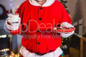 Santa Claus holding plate of sweet food with glass of milk