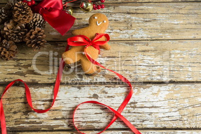 Gingerbread cookie tied with ribbon on wooden plank