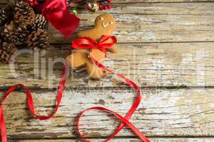 Gingerbread cookie tied with ribbon on wooden plank
