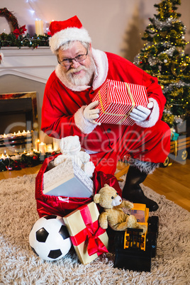 Portrait of santa claus holding gift box in living room