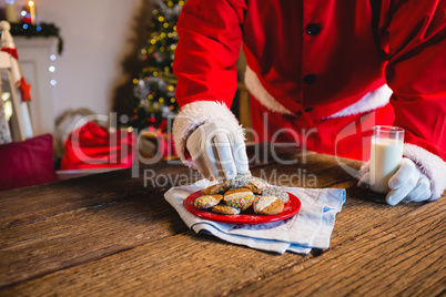 Santa Claus selecting a cookie with glass of milk