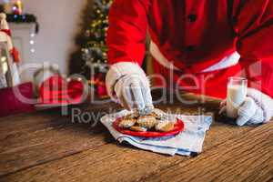 Santa Claus selecting a cookie with glass of milk