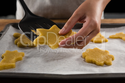 Man placing gingerbread cookies in baking tray