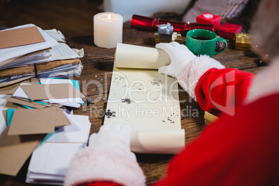 Santa Claus opening scroll with snowflakes