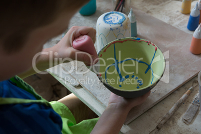 Boy painting a bowl in pottery shop