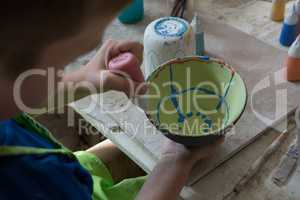 Boy painting a bowl in pottery shop