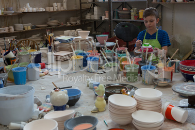 Boy painting a bowl in pottery shop