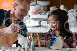 Male potter and girl painting bowl