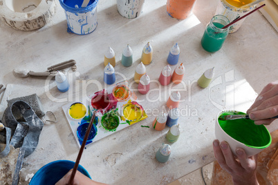 Hands of male potter and girl painting bowl