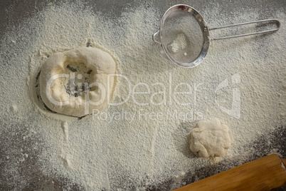 Dough, flour and stainer on table