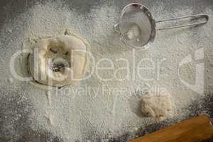 Dough, flour and stainer on table