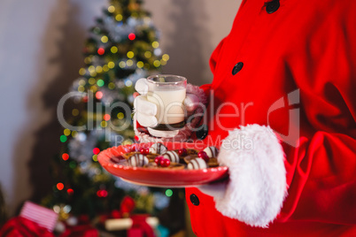 Santa Claus holding plate of sweet food with glass of milk