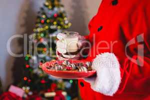 Santa Claus holding plate of sweet food with glass of milk