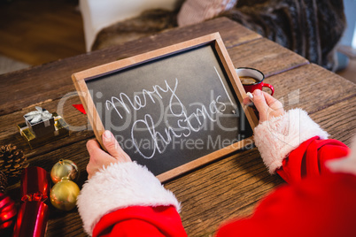 Santa Claus holding a slate with merry christmas text